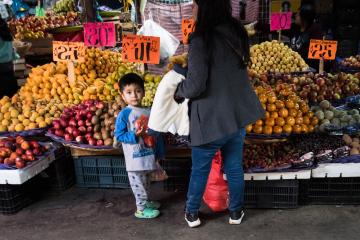 Adolescent boy shopping for produce with parent in Mexico