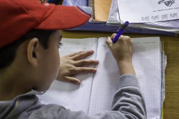 Child writing in his notebook at school