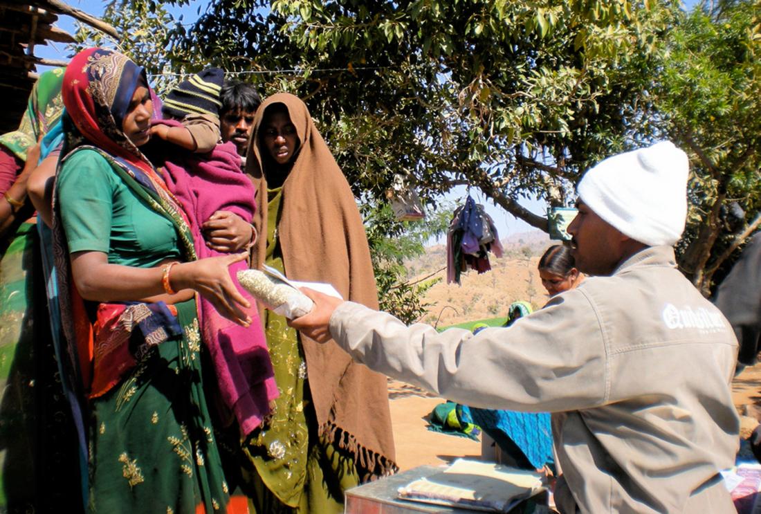 A parent receives a kilogram of lentils at a vaccination clinic in Rajasthan, India.