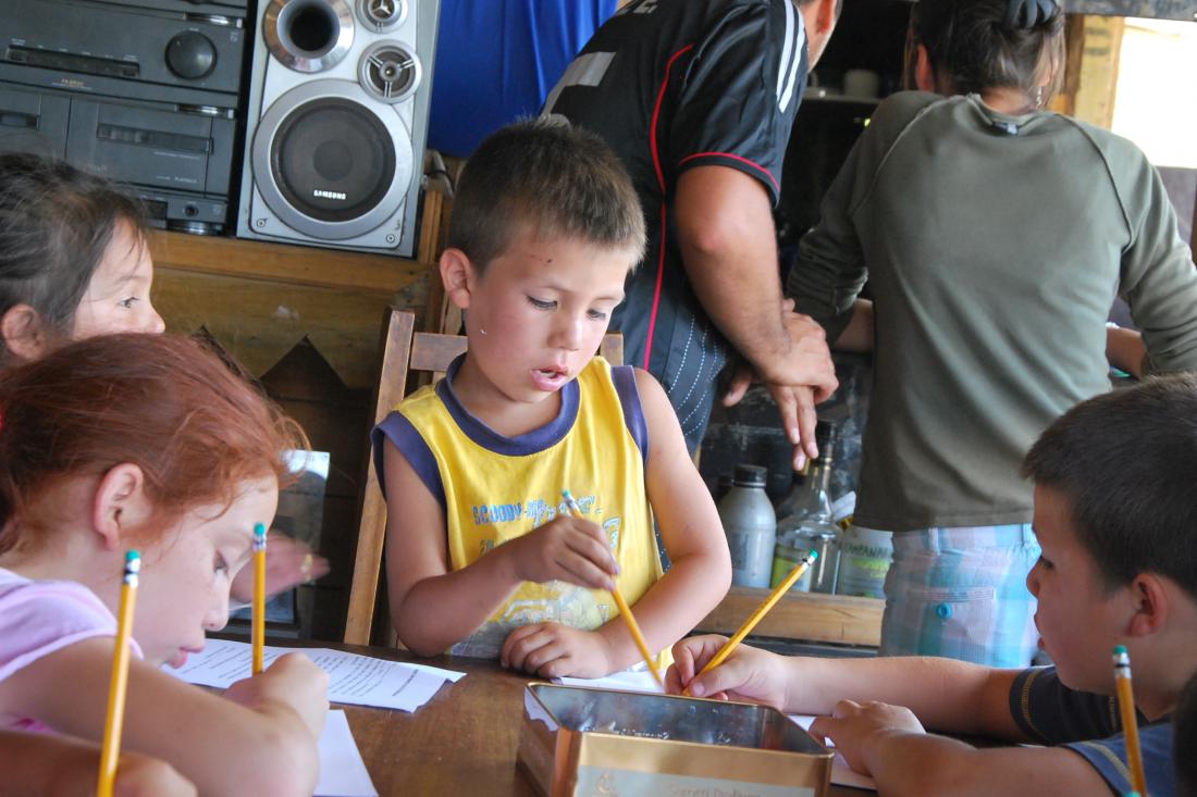 three children holding pencils and working on assignment