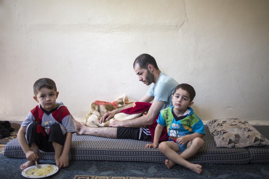 a father and two young boys sit in a living room