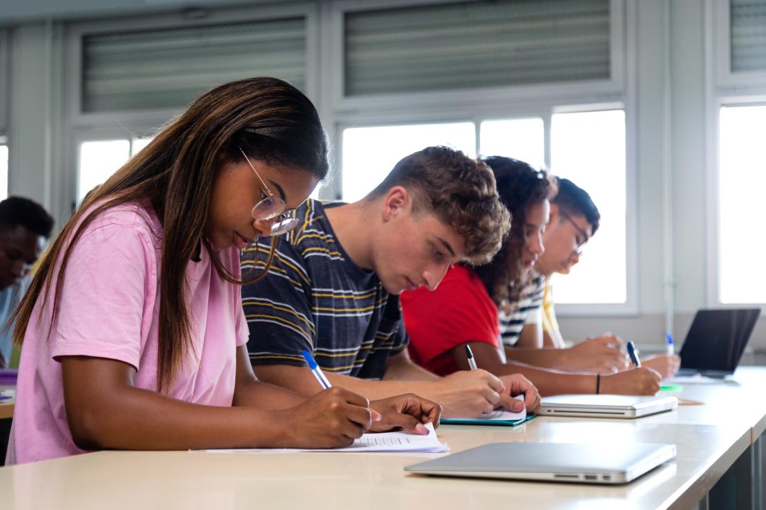 Students sit at a table and study for an exam.