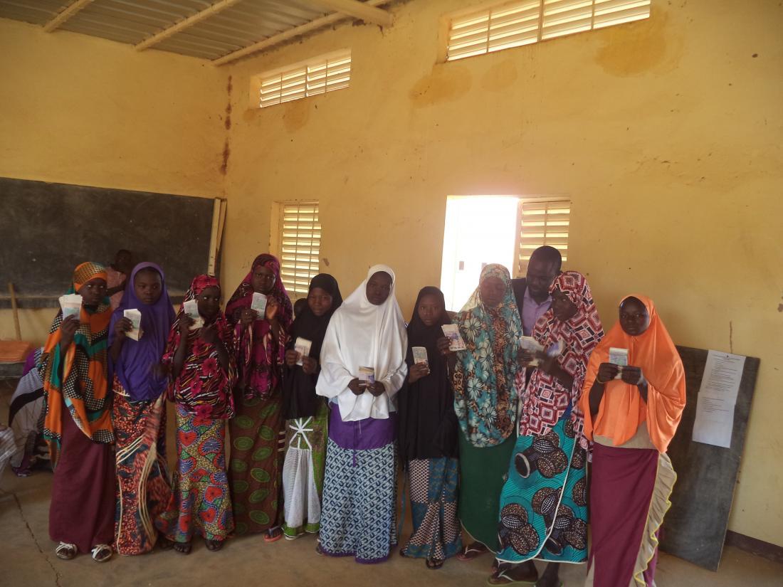 A group of girls receive stand in a row, holding their scholarships.