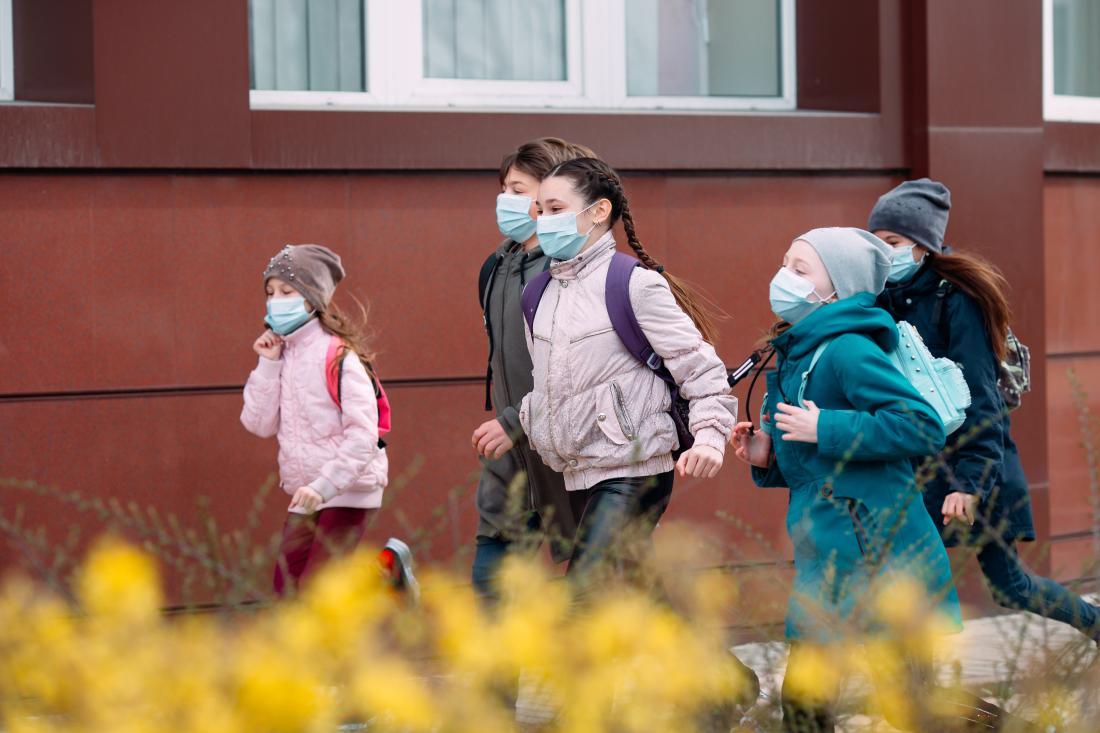 Children students in medical masks leave the schoo