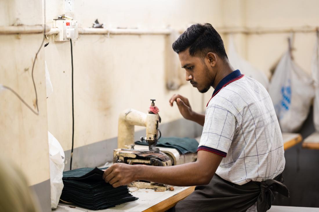 Man works at sewing station with pieces of black leather.