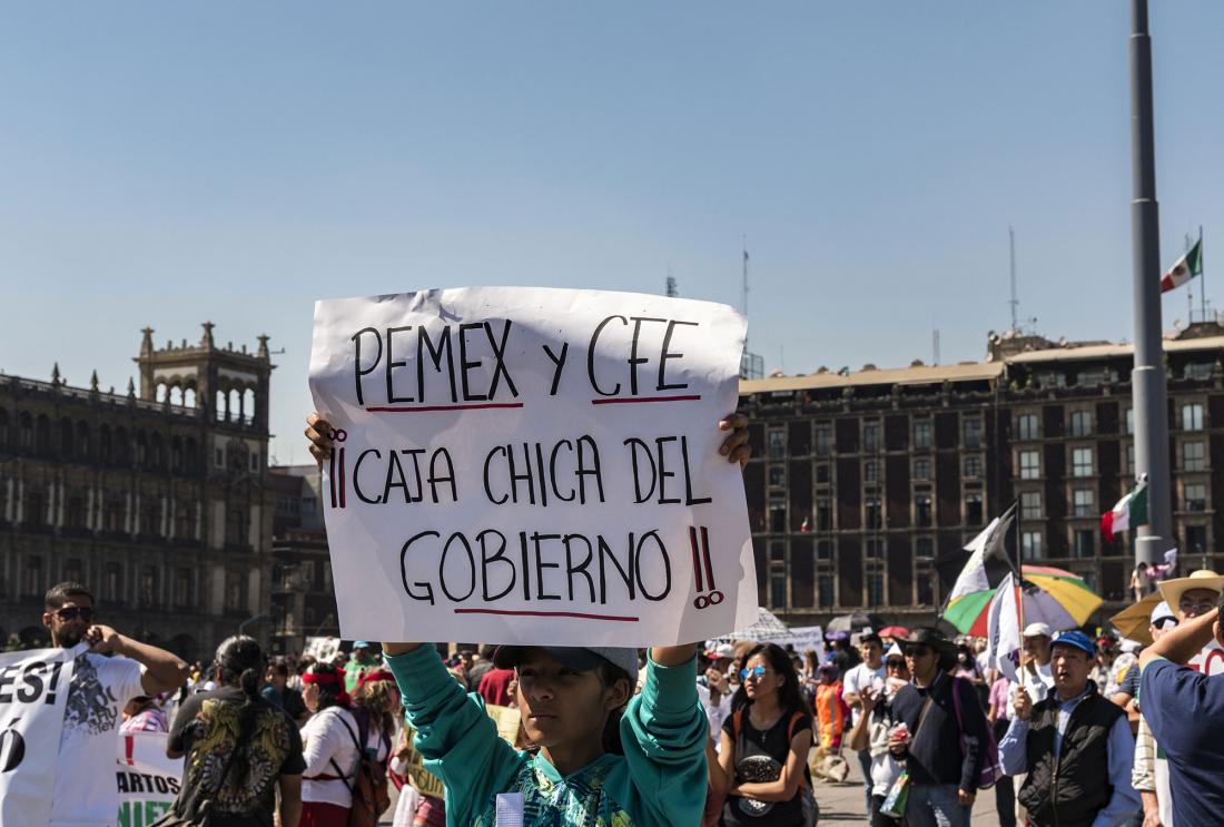 Woman holds sign reading "Pemex y CFE: Caja chica del gobierno"