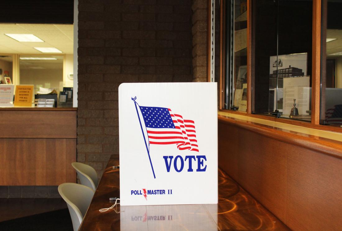 Empty polling place with privacy screen emblazoned with American flag and the word "vote"