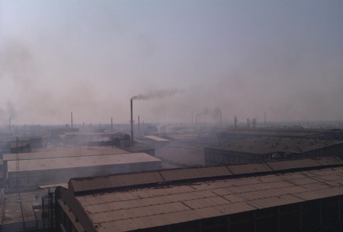 Smokestacks emit smoke into a hazy sky