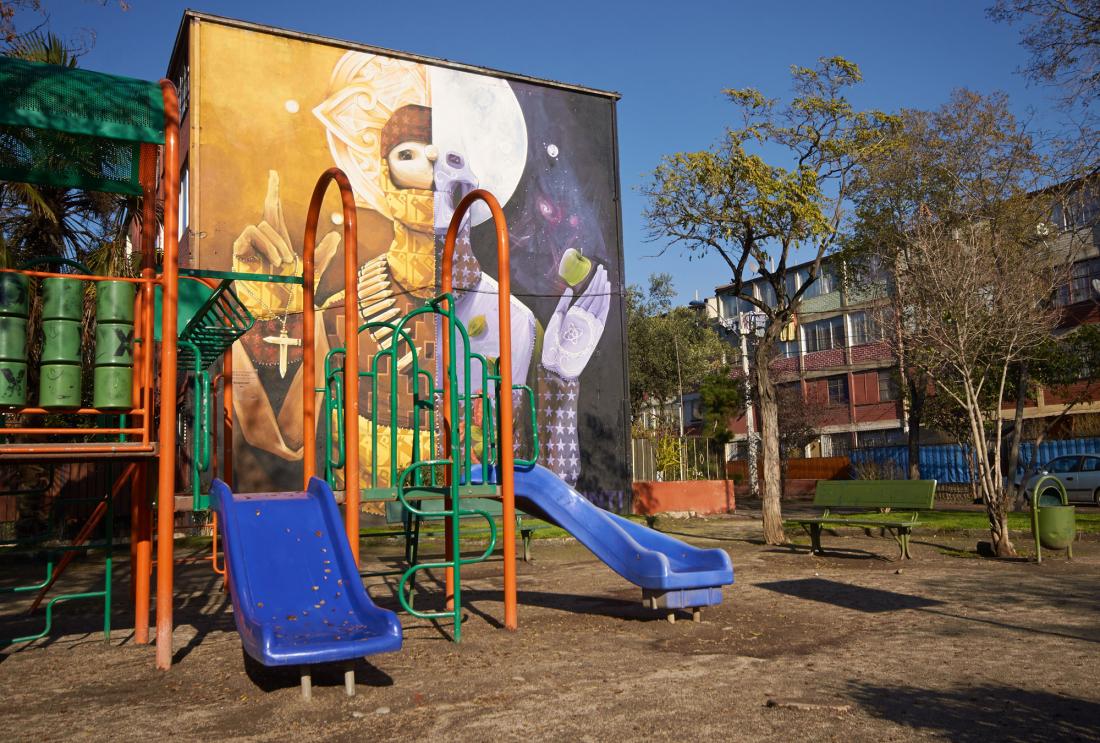 Playground in front of building with colorful mural