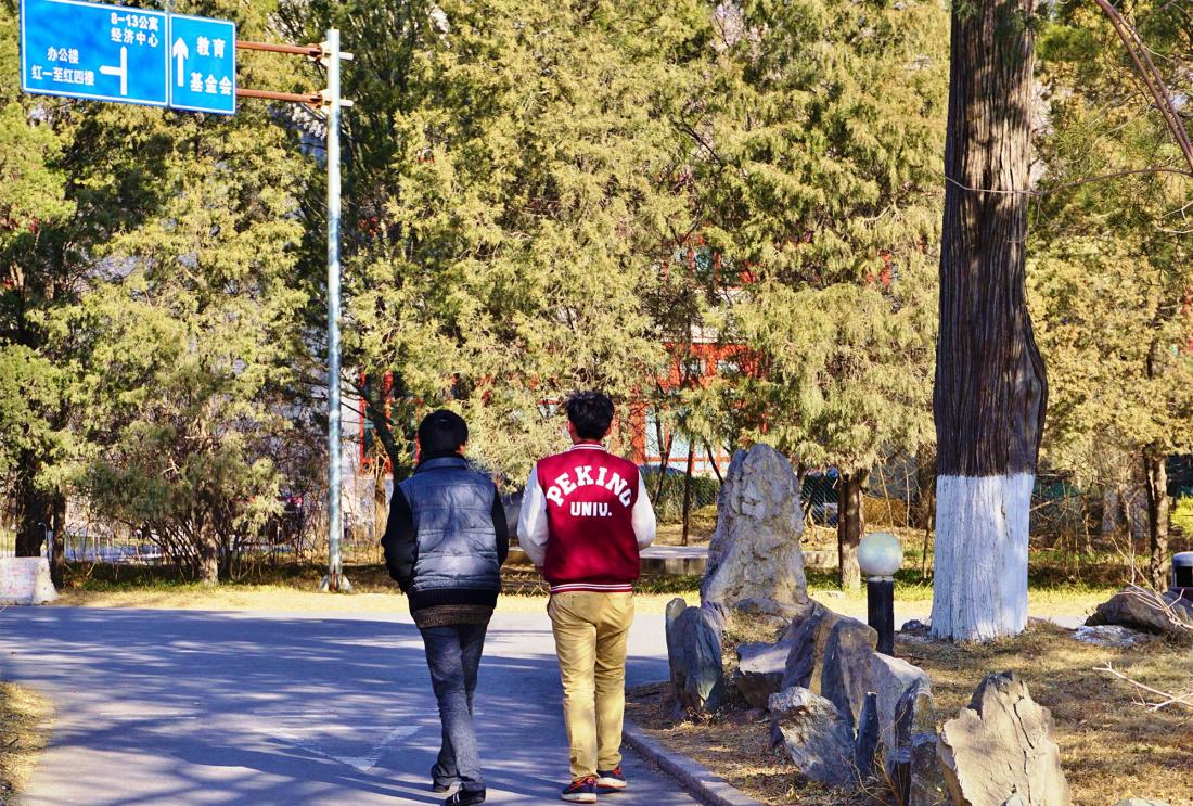 Two students walking: one's jacket reads 'Peking U"