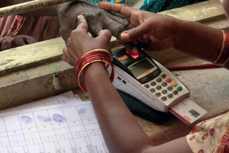 Woman holds a person's hand to a fingerprint machine