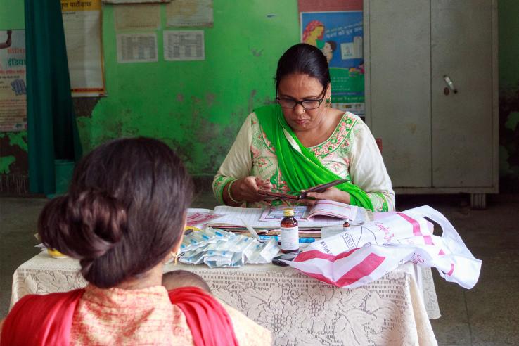 A nurse looks over a child's immunization records at a health clinic in Harayana, India in a government partnership supported by J-PAL.