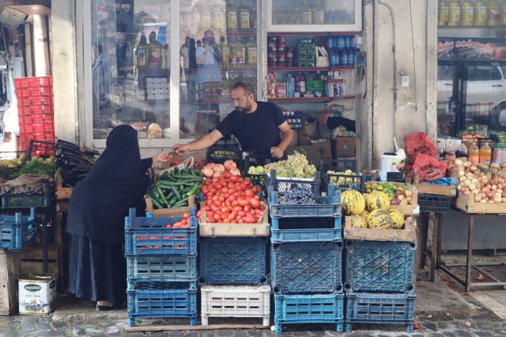 Market with fruits and vegetables. Women exchanges money with merchant for groceries.