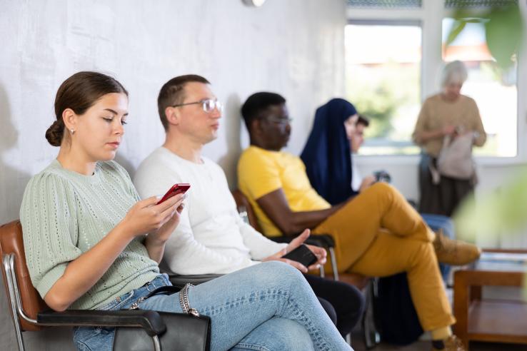 Female brunette youth looks at her phone while waiting in an employment office in France