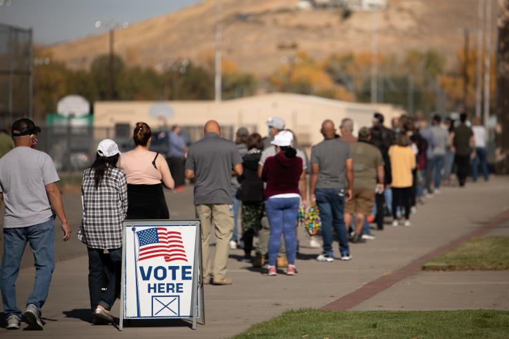 View of voter turnout in the United States with "vote here" sign and american flag