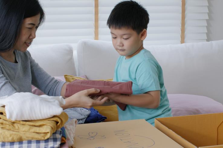 A young boy and a woman pack clothes they are donating in the United States