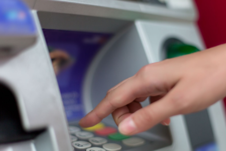 Close up of female hand entering PIN pass code on ATM bank machine keypad