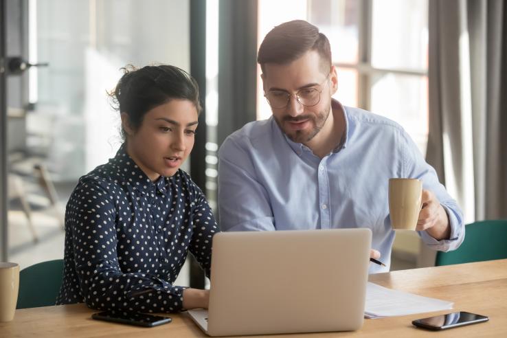 Two people sitting behind the laptop working together