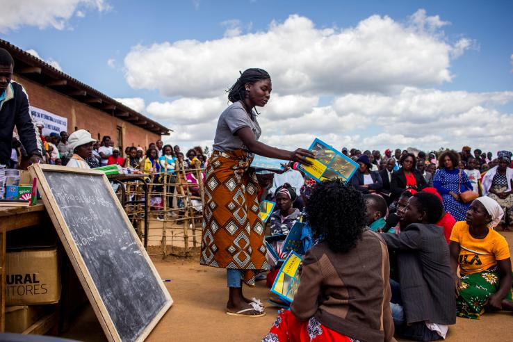 Woman giving numeracy books on International Literacy Day in Mozambique