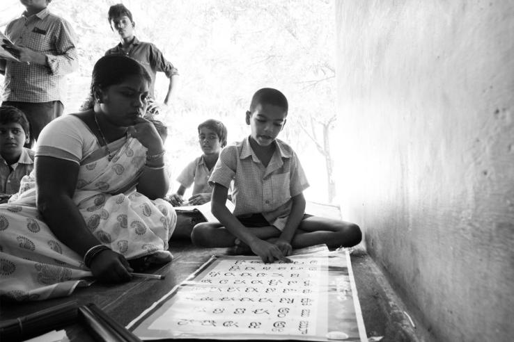 A teacher assists student in reading the alphabet