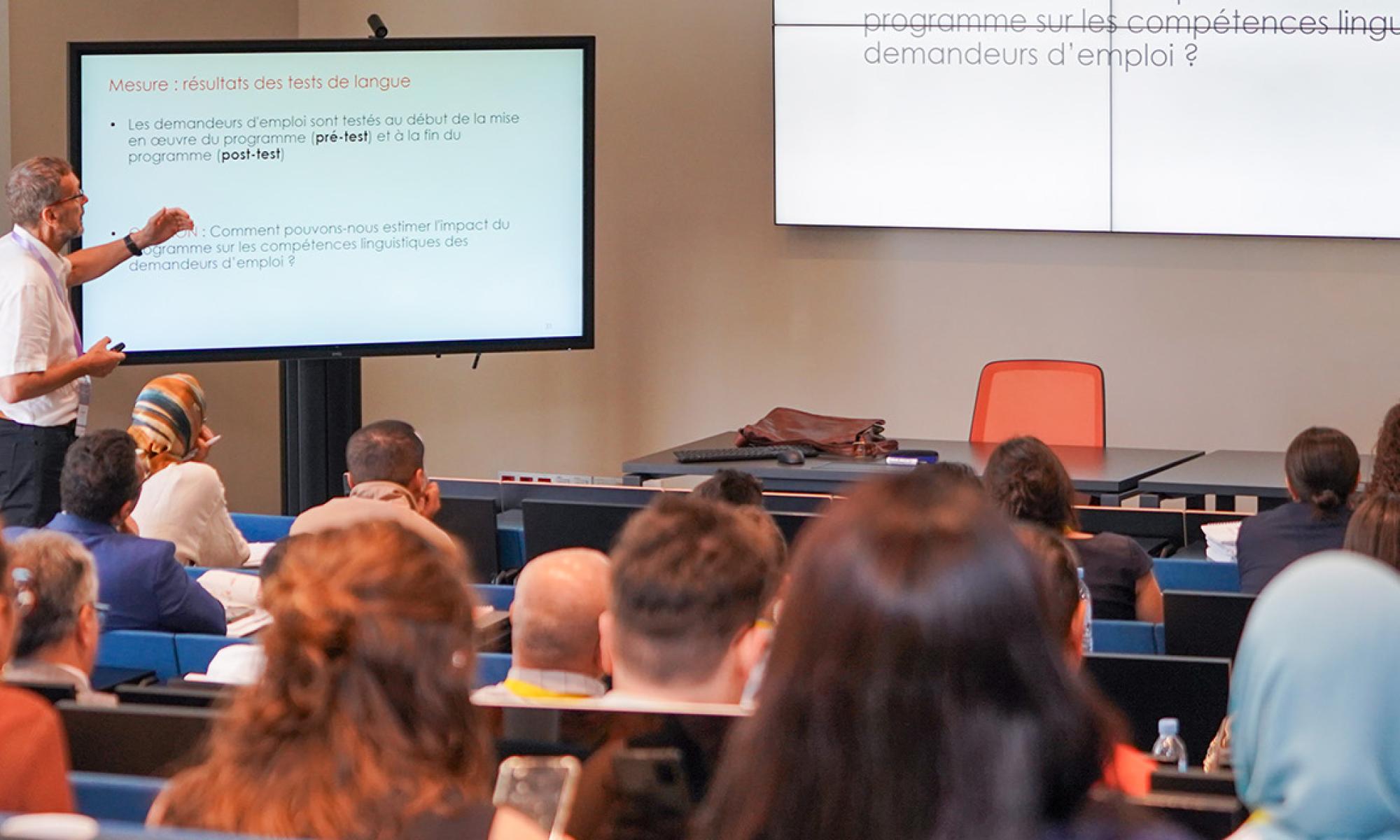 Man standing in front of slide presenting in front of a large audience