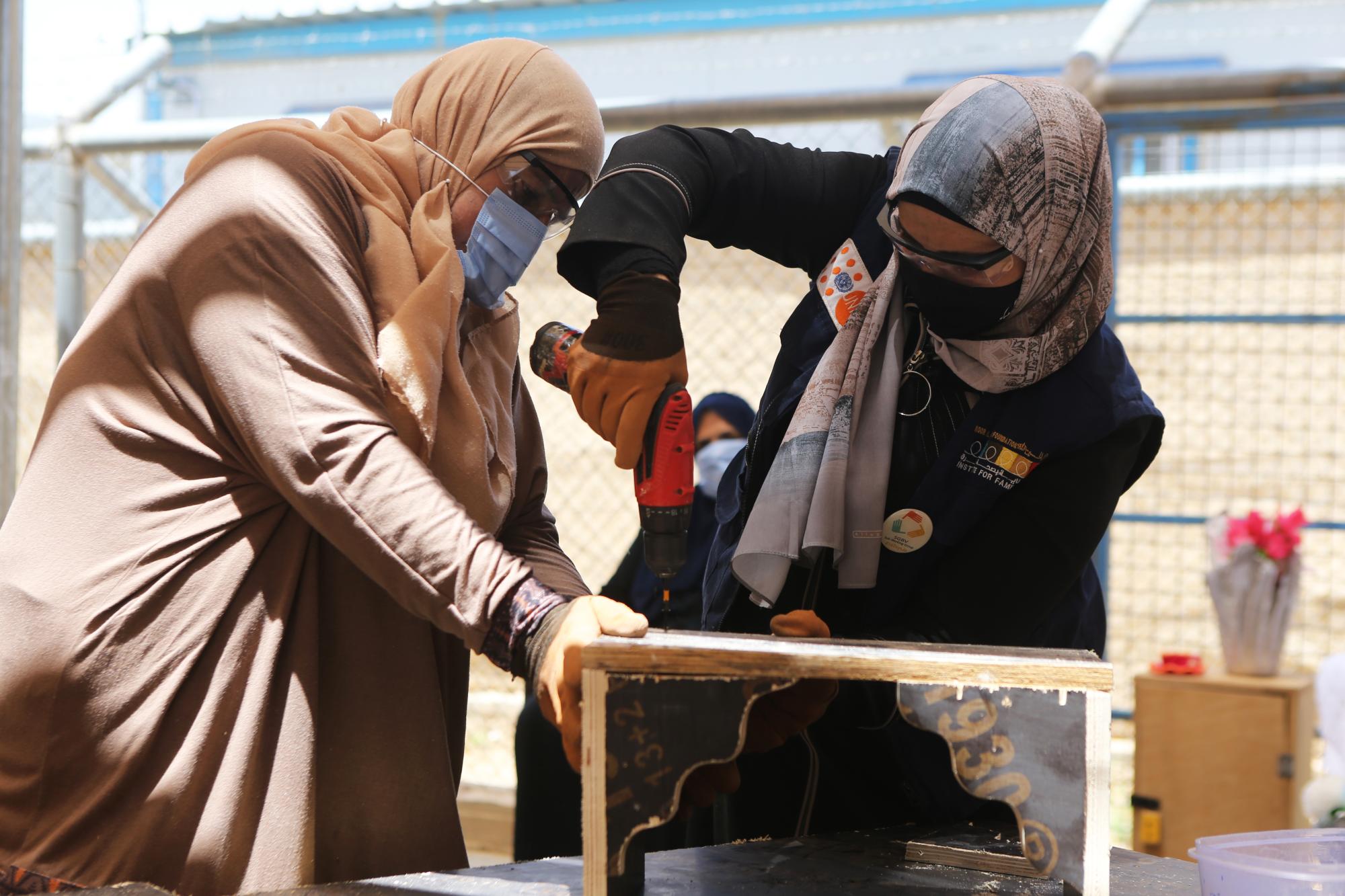 Two women working together to build a shelf