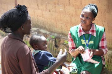 Woman in uniform talks to woman with baby in her lap