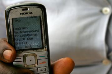 Man holds up phone showing message of mobile money received from GiveDirectly