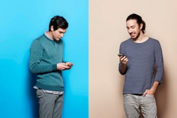 Two men communicate on cell phones.