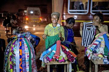 Two women sell clothing at a stand on a street