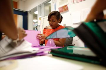 woman sitting at table and opening pink folder