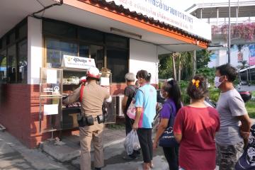 People wearing masks stand in line to receive food from police