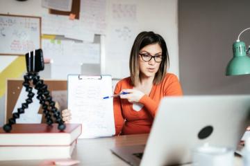 women holding up notepad in front of a computer to as a tutor 