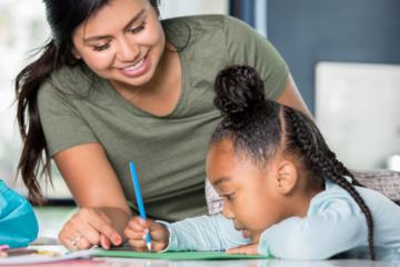 a tutor assisting a little girl working on an assignment