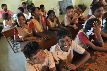 A group of children sitting inside a classroom in school 