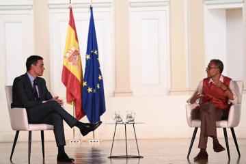 Prime Minister Sánchez speaking with Abhijit Banerjee on a stage.