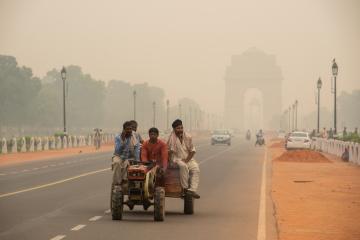 Municipal workers on vehicle in Rajpath, Delhi engulfed by smog