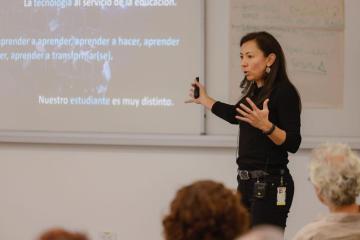 A woman gives a lecture and gestures with her hands.