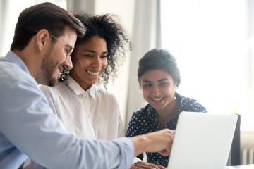 Three people smiling looking at computer screen together