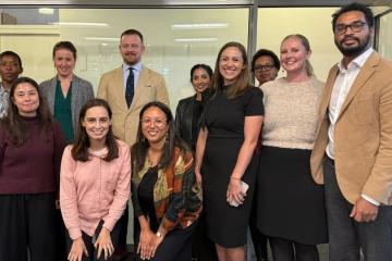 A group of people pose for a photo while standing in a conference room.