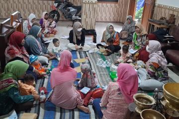 A group of women sit in a circle playing with their young babies