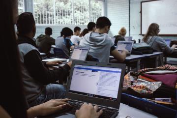A student sits with their hands on a laptop keyboard with the screen displaying an AI writing assistant.